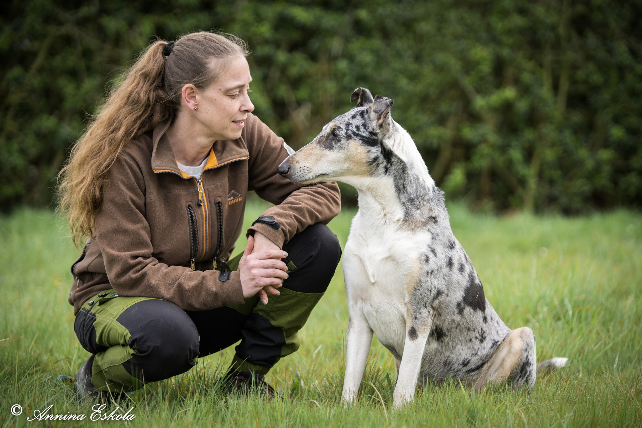 Ursula Ljungberg med sin korthåriga collie sittandes på en gräsmatta.