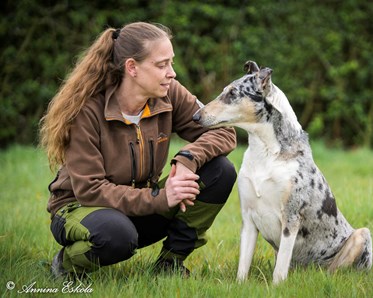 Ursula Ljungberg med sin korthåriga collie sittandes på en gräsmatta.