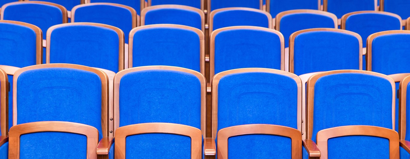 Bild som visar många blå konferensstolar på rad