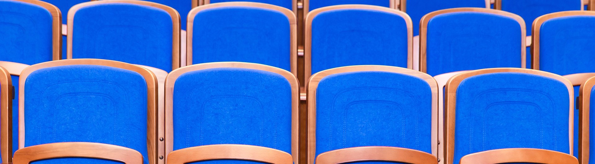 Bild som visar många blå konferensstolar på rad