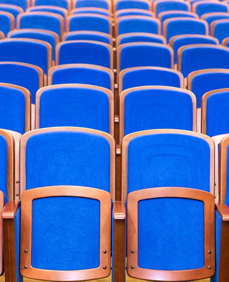 Bild som visar många blå konferensstolar på rad
