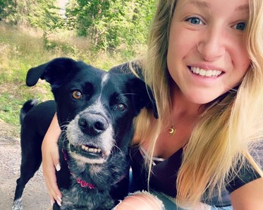 Bild på Sara Stolt som glatt håller armen om sin hund,