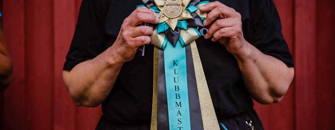 Människa håller i klubbmästerskapsrosett