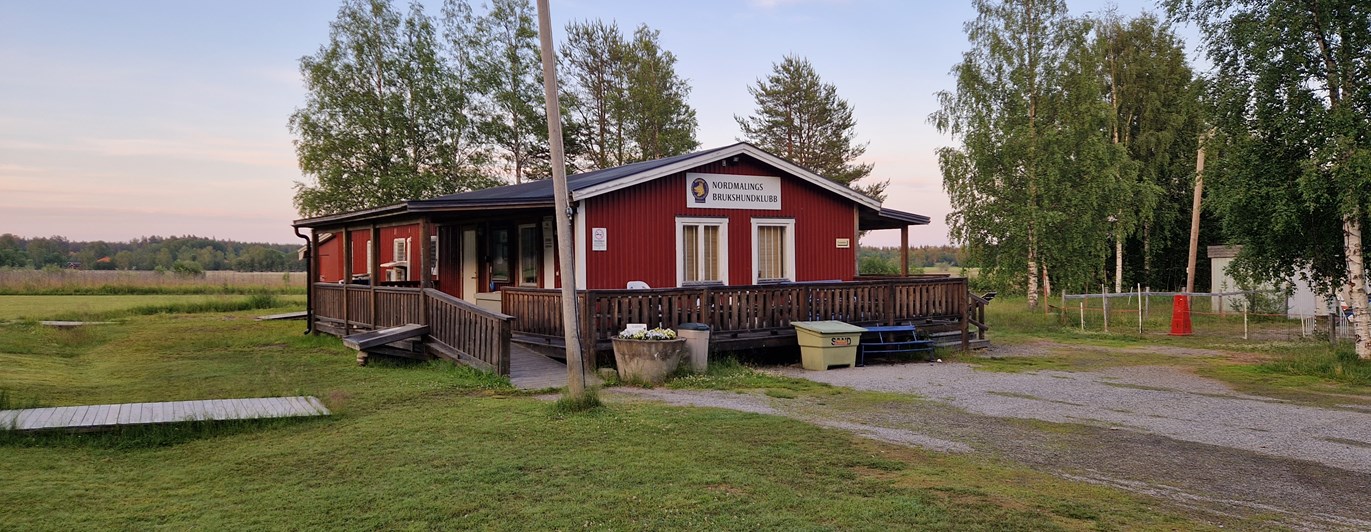 foto på klubbstuga. Rött hus med altan