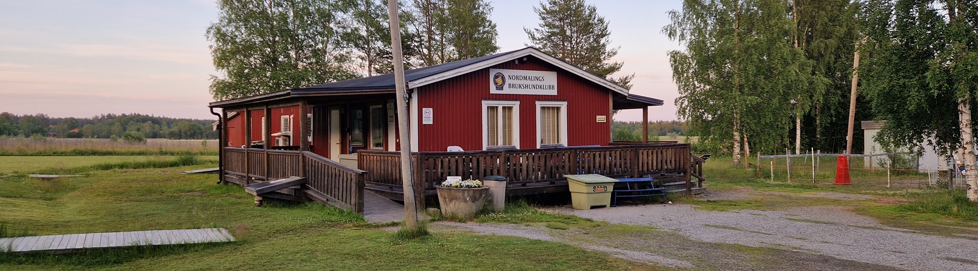 foto på klubbstuga. Rött hus med altan