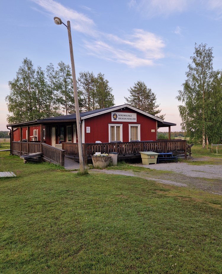 foto på klubbstuga. Rött hus med altan