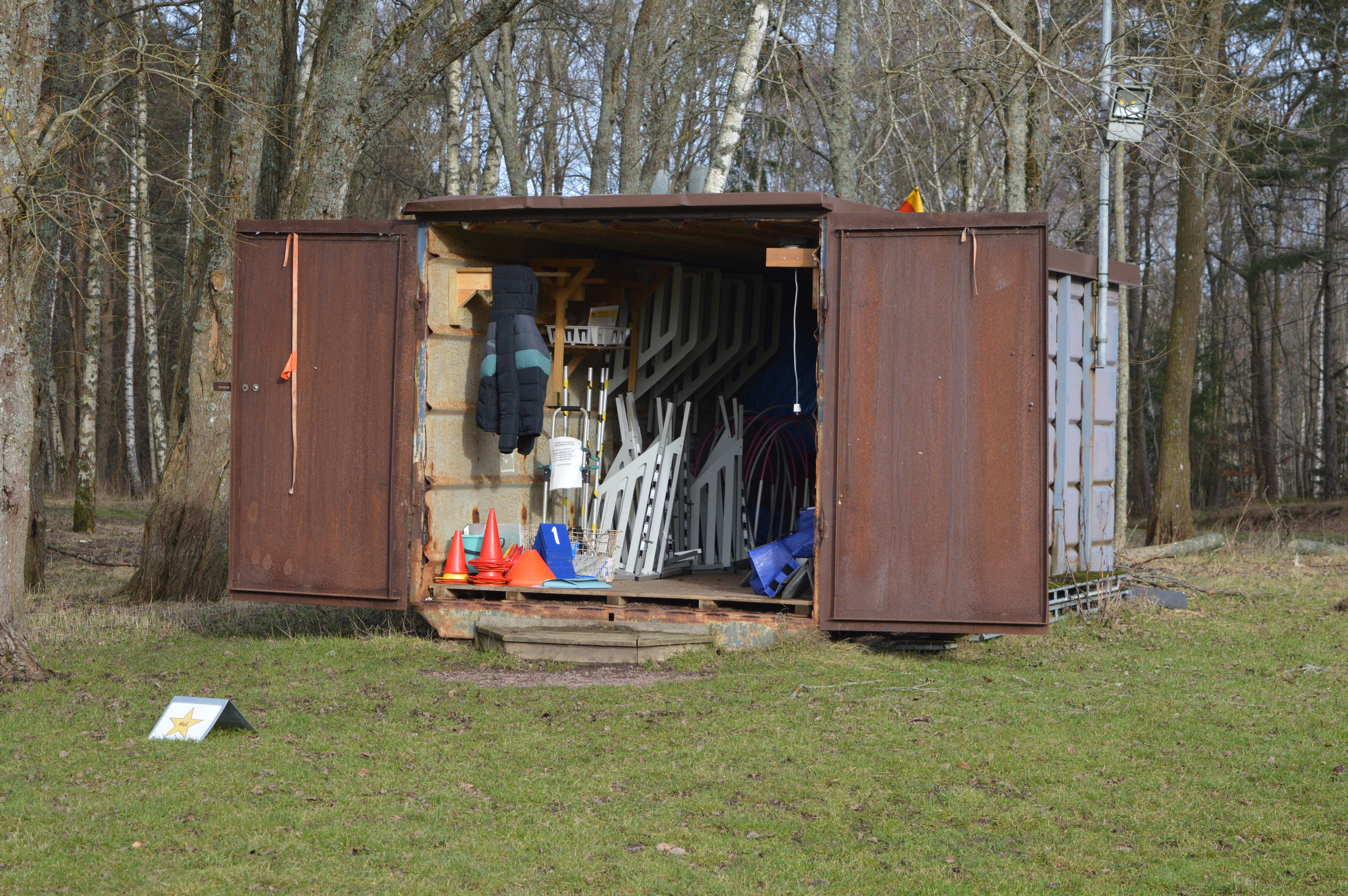 Bild på klubbens bruna container som innehåller rallylydnadsskyltar och agilityhinder.