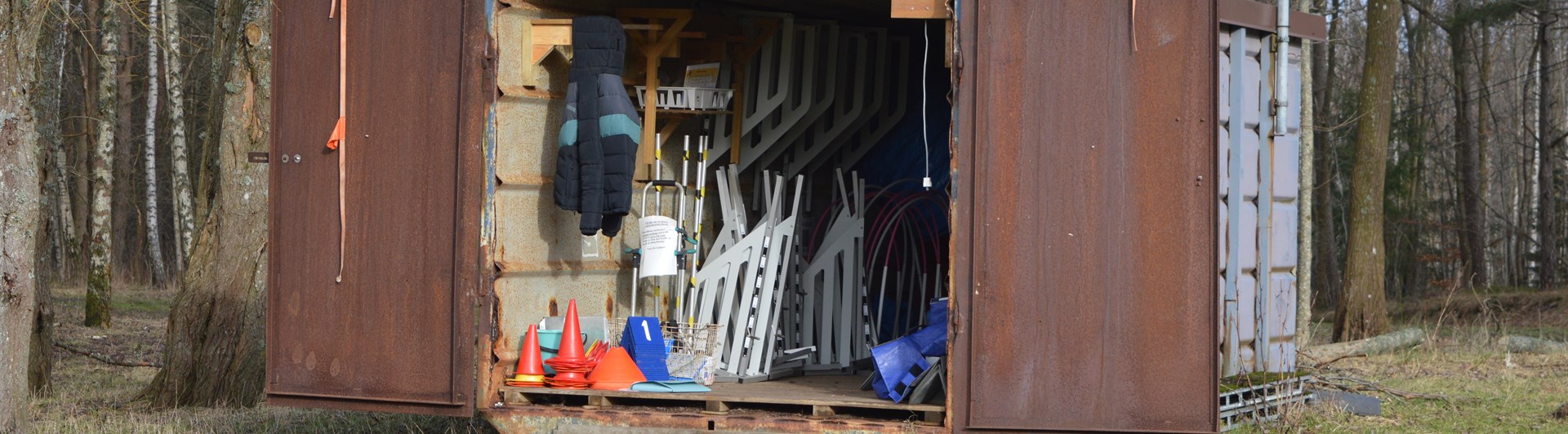 Bild på klubbens bruna container som innehåller rallylydnadsskyltar och agilityhinder.