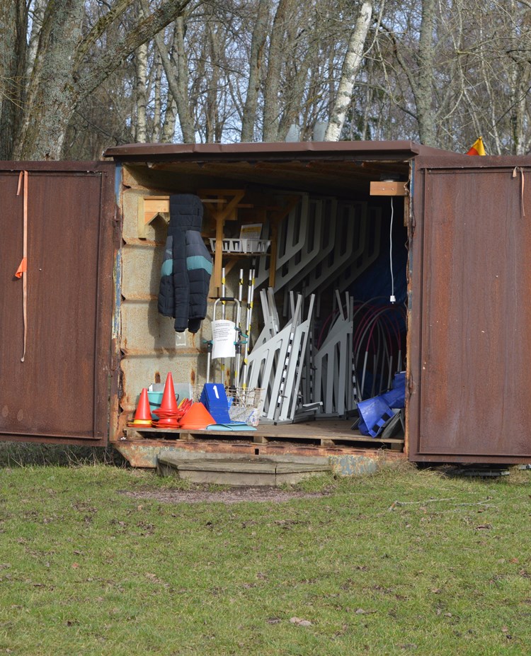 Bild på klubbens bruna container som innehåller rallylydnadsskyltar och agilityhinder.