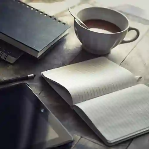 Bild som visar administration på ett bord med ipad, kaffemugg, skrivblock och penna.