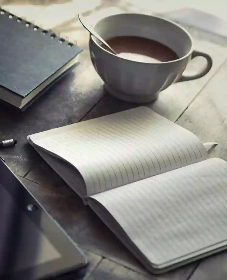 Bild som visar administration på ett bord med ipad, kaffemugg, skrivblock och penna.
