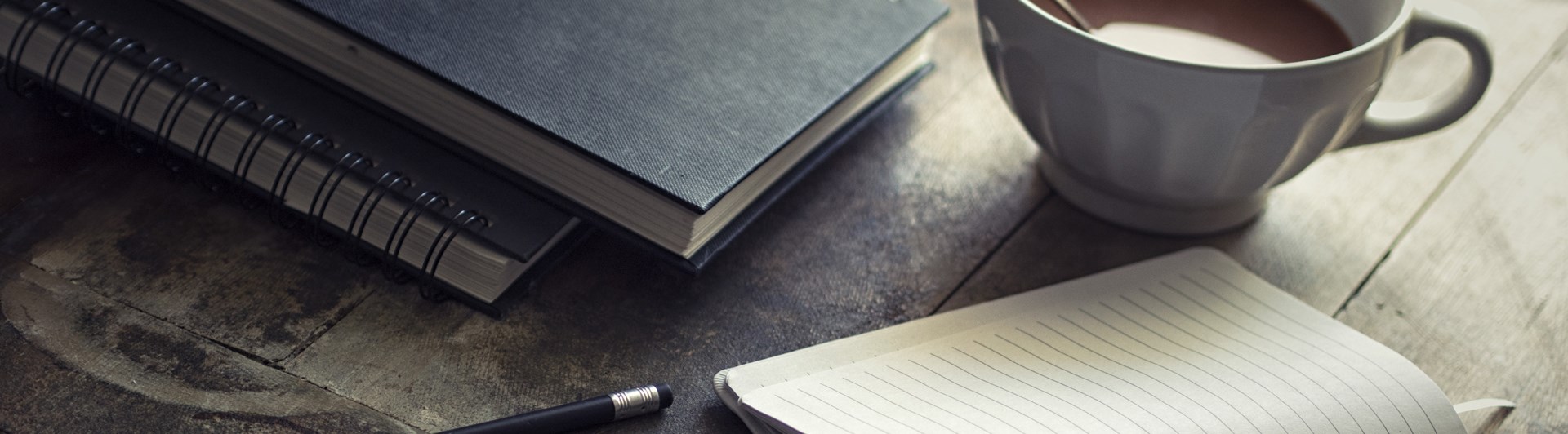 Bild som visar administration på ett bord med ipad, kaffemugg, skrivblock och penna.