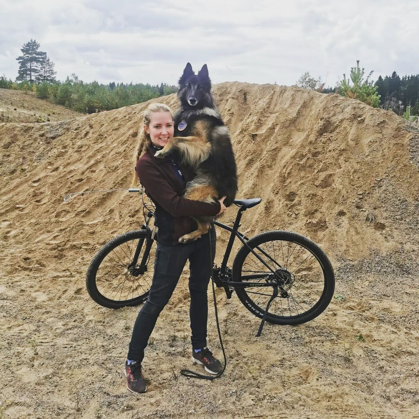 Bild på en hundförare som håller sin belgiska vallhund Thilo i famnen.