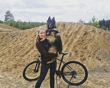 Bild på en hundförare som håller sin belgiska vallhund Thilo i famnen.