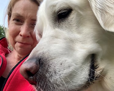 Anna Erlandsson, självporträtt, med golden retriever närmast kameran.