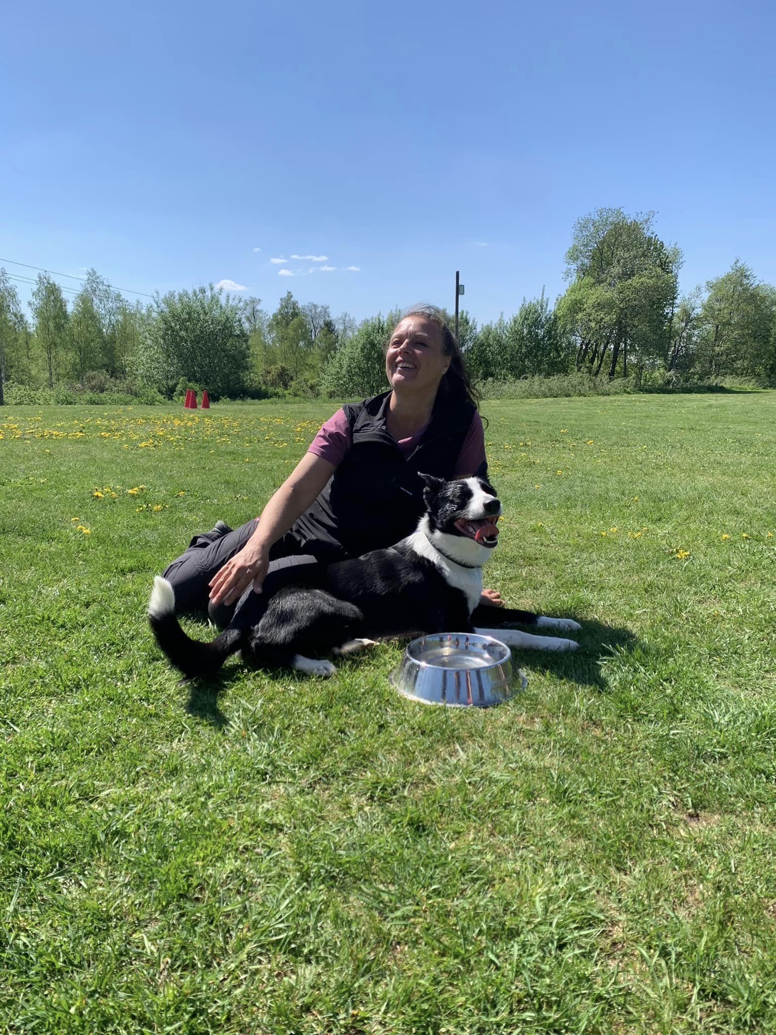 Hund och förare sitter i gräset