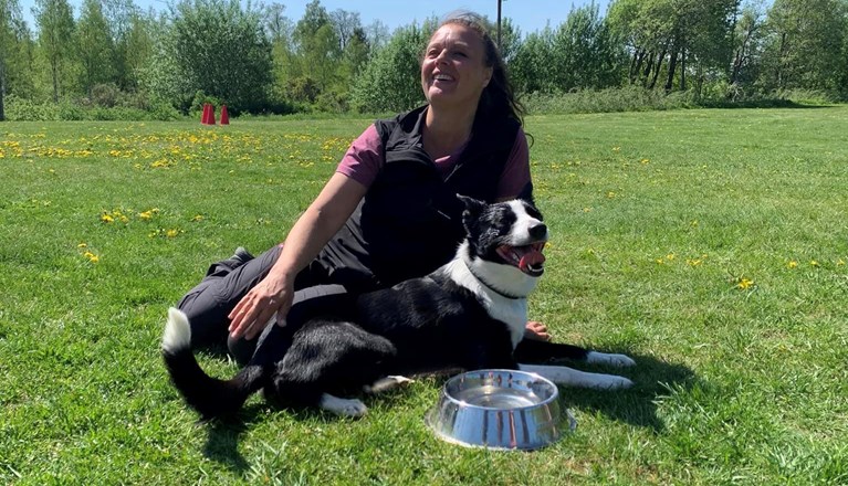 Hund och förare sitter i gräset