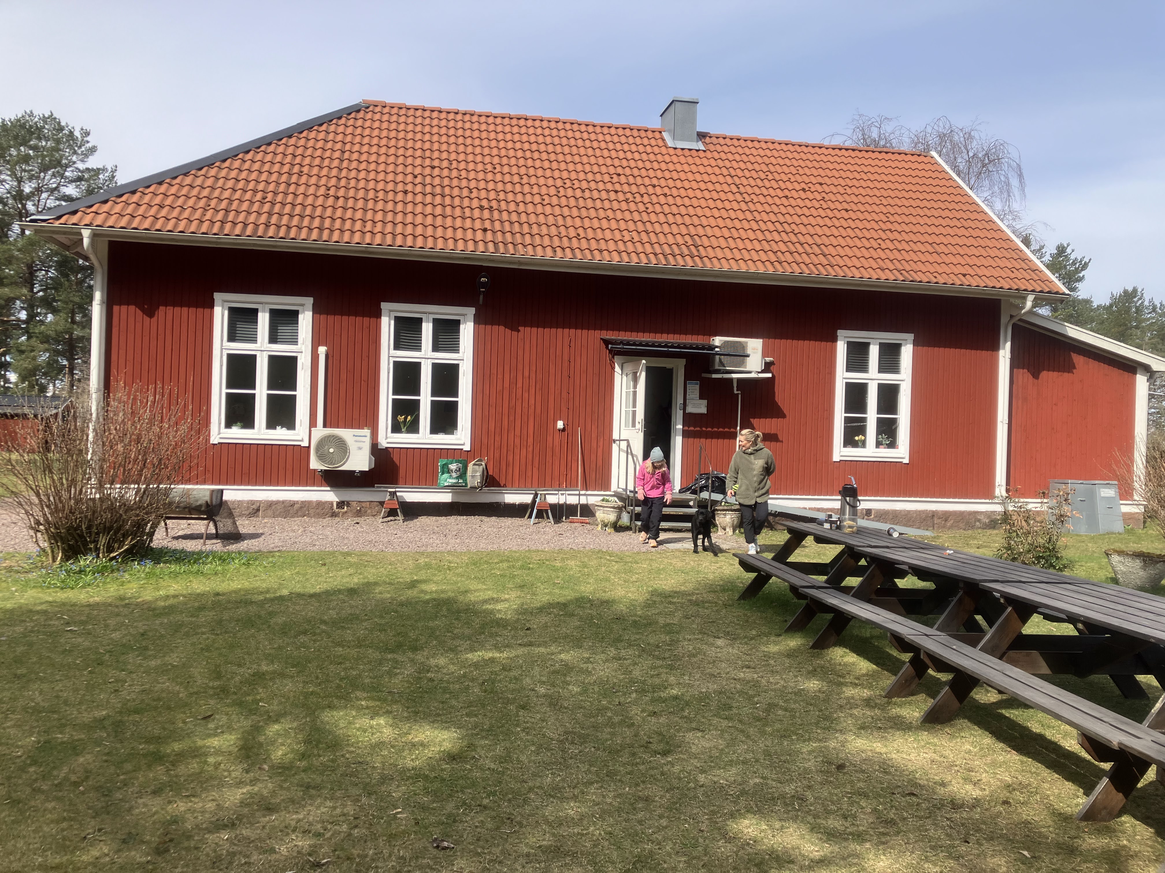 Människor och hund går ut ur klubbstuga