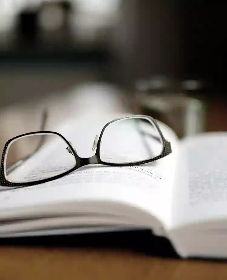 Bild som visar ett par glasögon som ligger på en uppslagen bok.