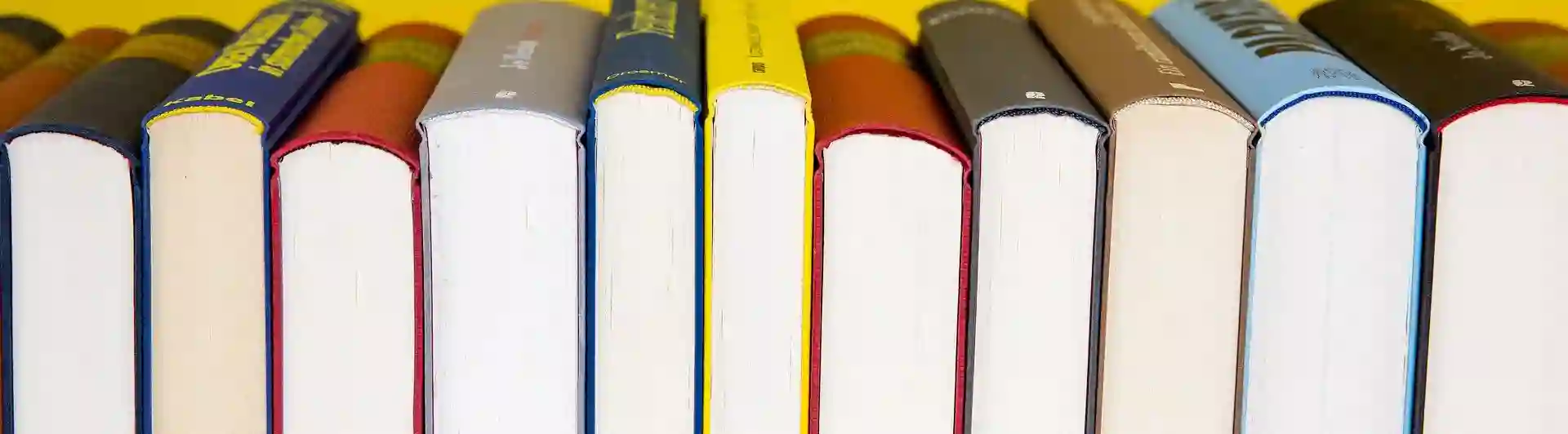 Bild som visar flera böcker framför gul bakgrund.