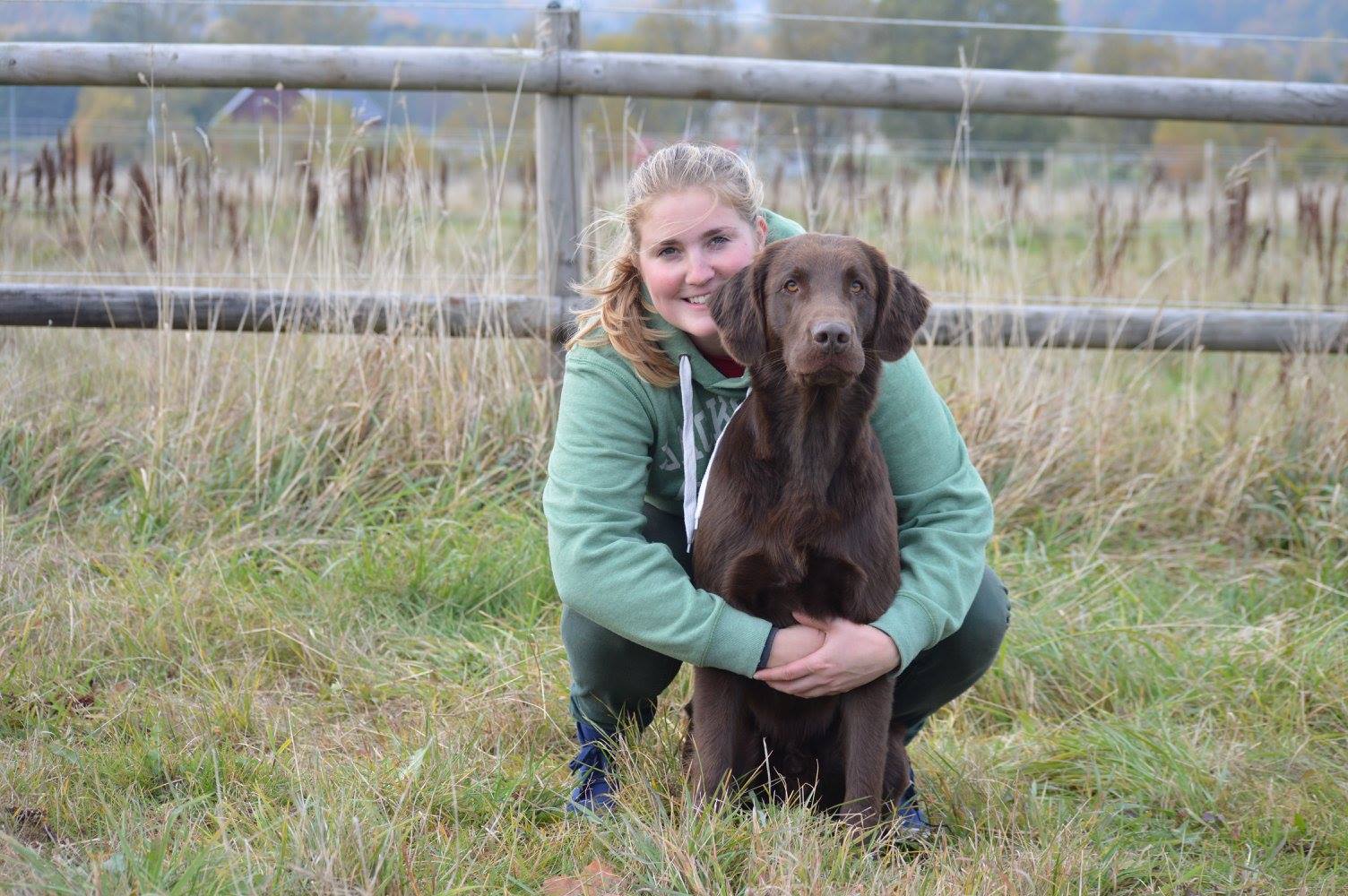 En bild på ett ekipage där föraren kramar om sin bruna hund