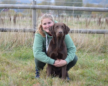 En bild på ett ekipage där föraren kramar om sin bruna hund
