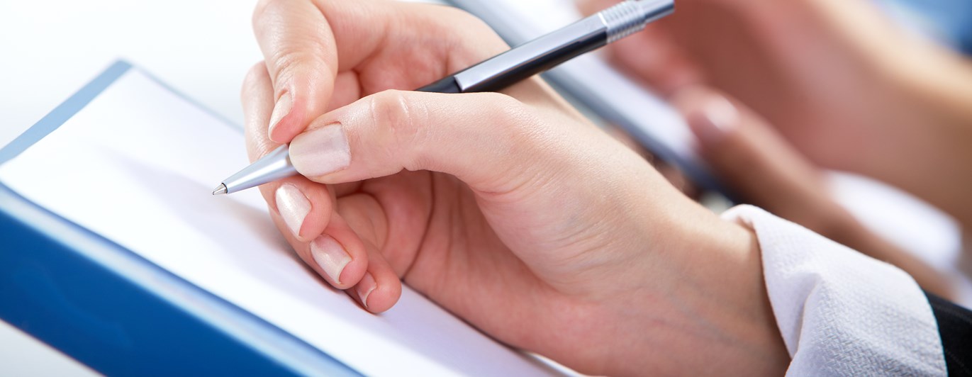 Hand som håller i en penna och skriver