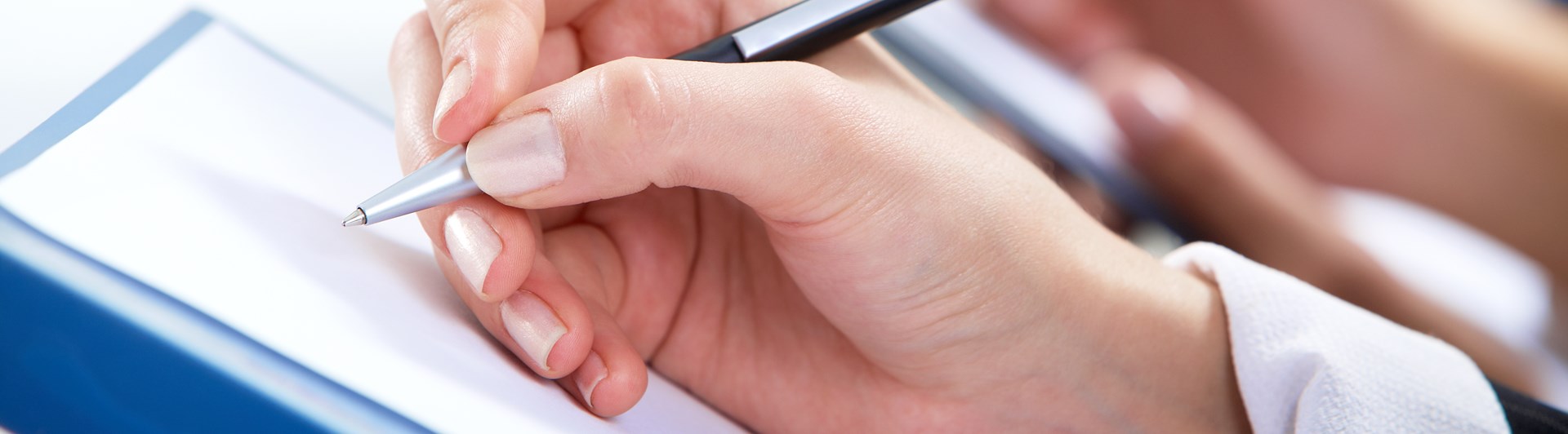 Hand som håller i en penna och skriver