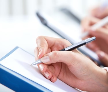 Hand som håller i en penna och skriver