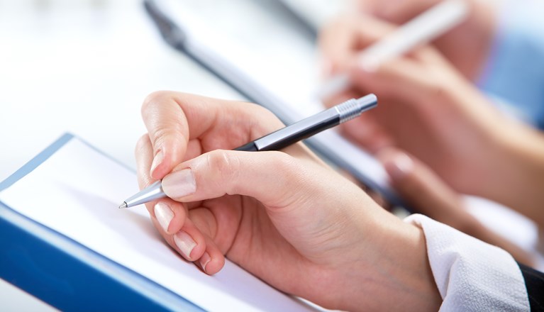 Hand som håller i en penna och skriver