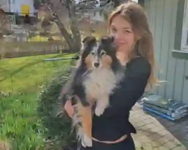 En tjej som håller sin hund i famnen.