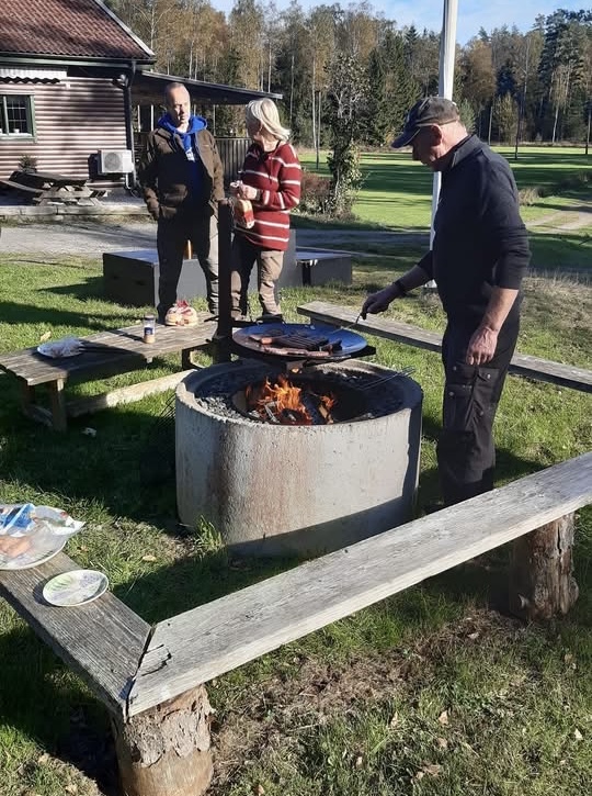 Tre människor står runt en grillplats