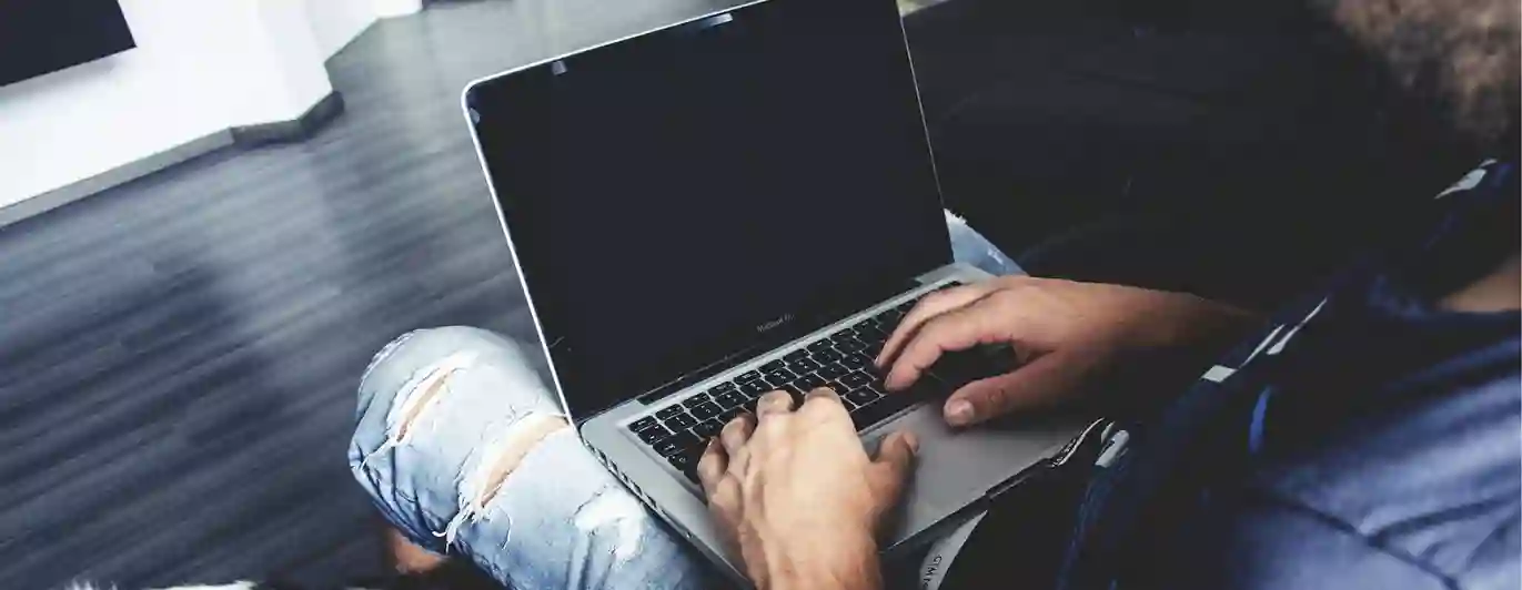 En man som sitter vid datorn med en hund bredvid sig