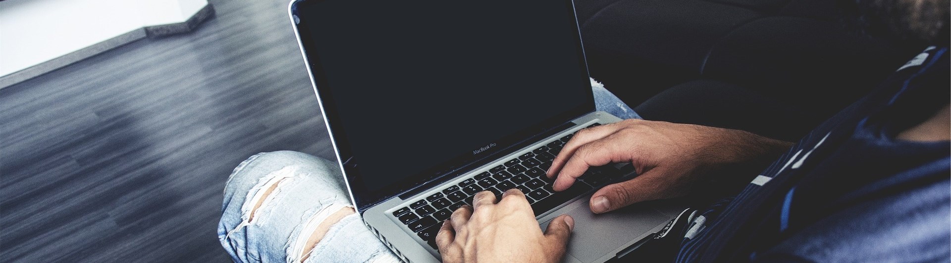 En man som sitter vid datorn med en hund bredvid sig