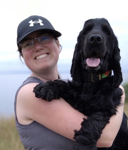 Elin som håller sin svarta cockerspaniel i sin famn högt upp i ansiktetshöjd