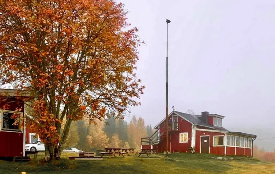 Bild på Örnsköldsviks Brukshundklubbs klubbstuga med höstfärger på träden runtom