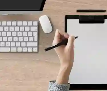 Bild som visar en skrivande hand på papper på ett skrivbord.