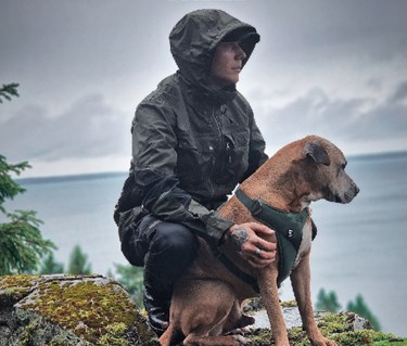 Reklambild för Arrak, man i regnponcho klappar en hund
