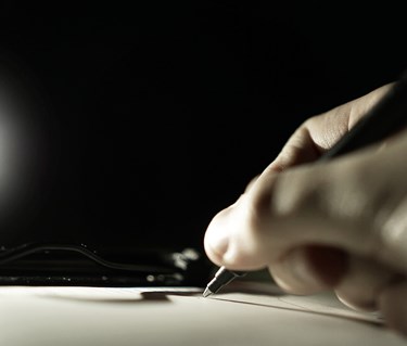 Bild som visar skrivande hand med kulspetspenna.