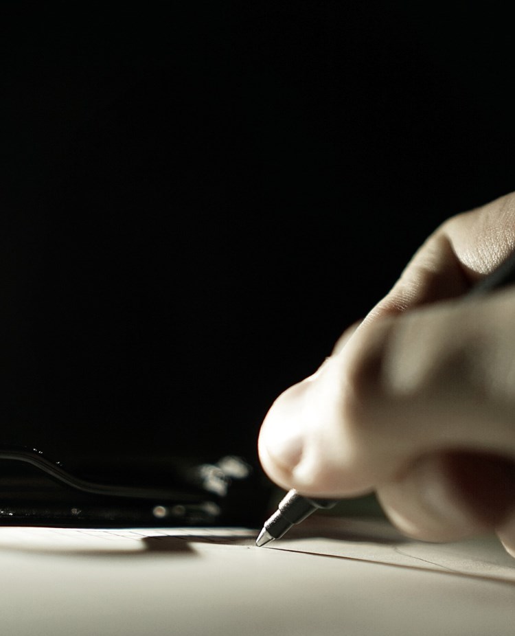 Bild som visar skrivande hand med kulspetspenna.