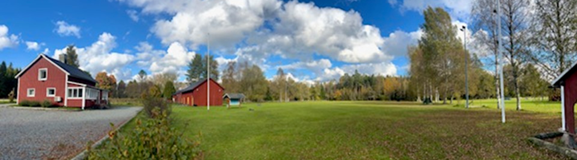 Röd klubbstuga och en stor appellplan.