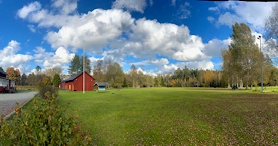Röd klubbstuga och en stor appellplan.