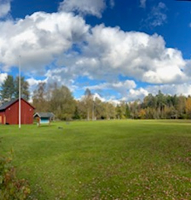 Röd klubbstuga och en stor appellplan.