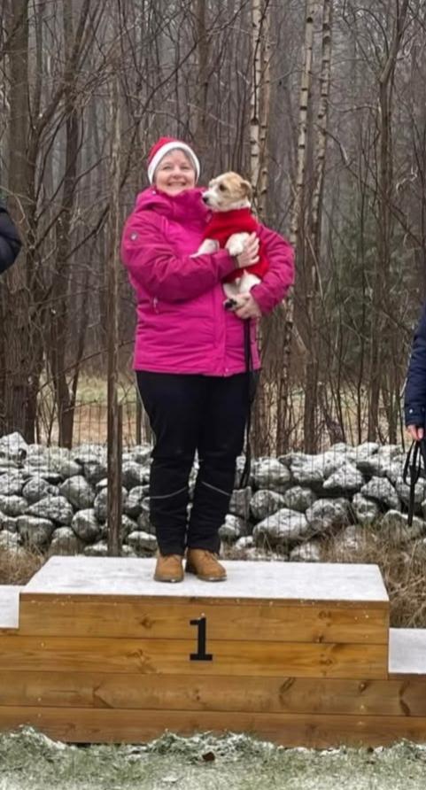 Bild på Lis-Beth på prispallen med en hund i famnen. Hon bär tomteluva och rosa jacka.