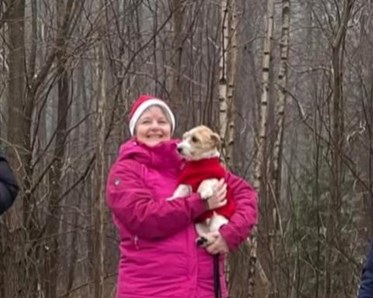 Bild på Lis-Beth på prispallen med en hund i famnen. Hon bär tomteluva och rosa jacka.