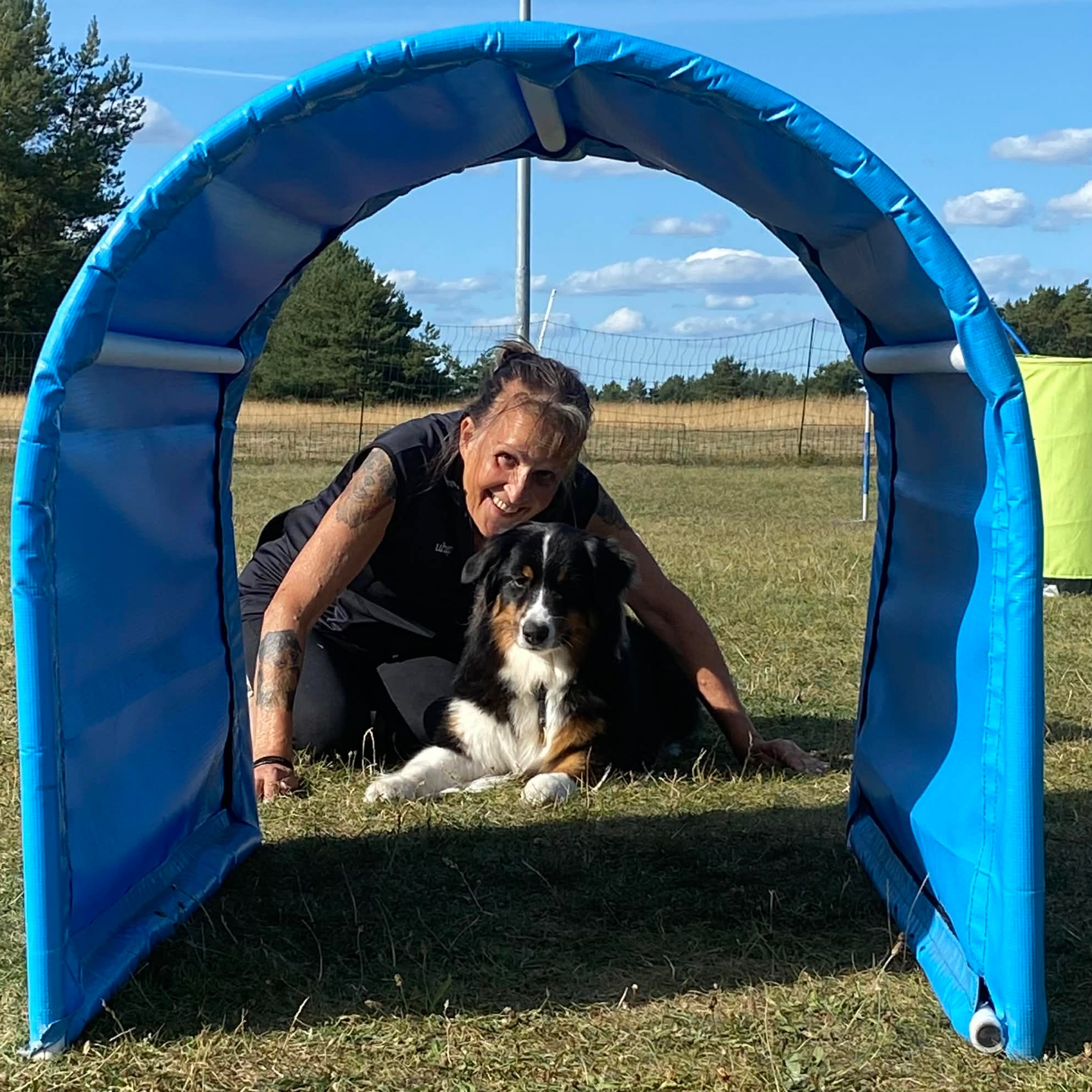 Bild på när Susanne Månsson och hennes hund Mimmi tittar igenom ett hoopershinder