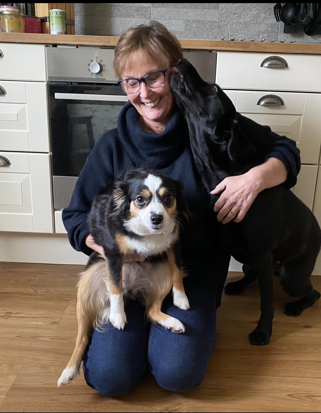 Kvinna med två hundar där den ena hunden slickar henne i ansiktet