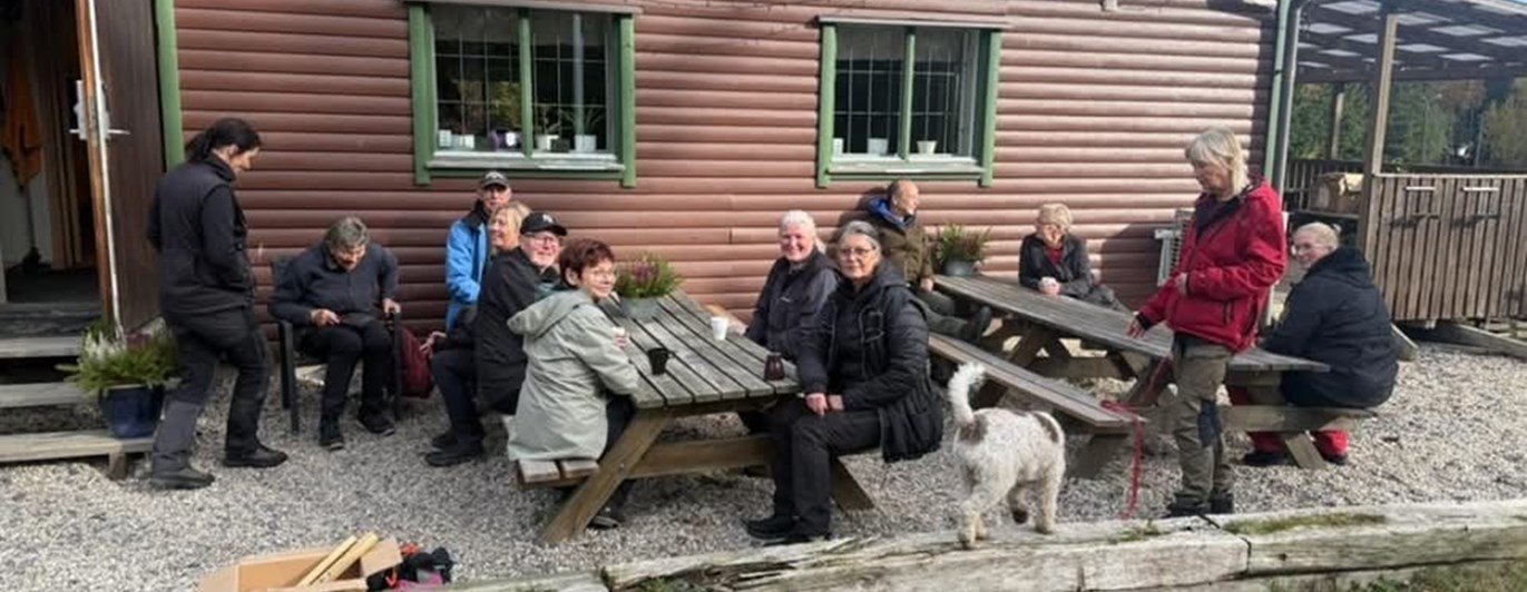 Människor sitter utomhus framför ett klubbhus