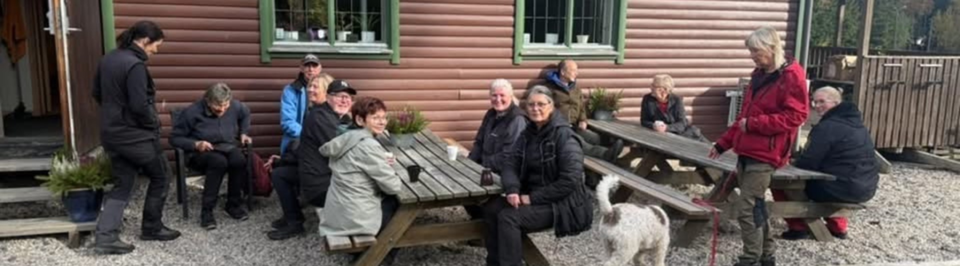 Människor sitter utomhus framför ett klubbhus