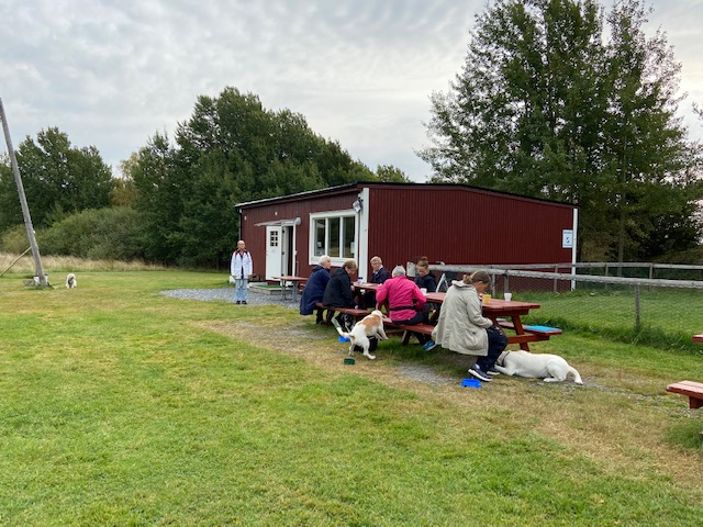 Hundägare som fikar utanför klubbstugan.